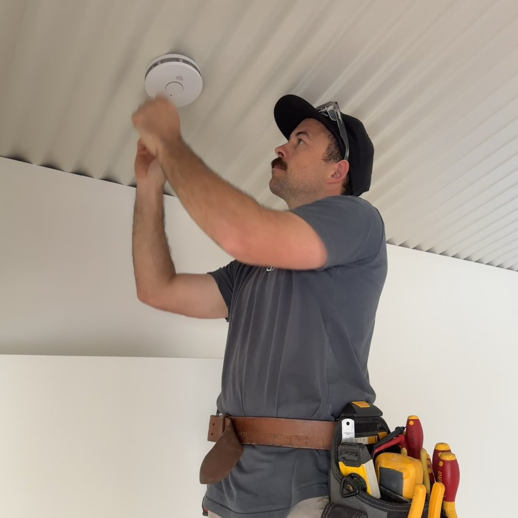 Ultralec electrician installing a smoke alarm on a ceiling in the Noosa Hinterland