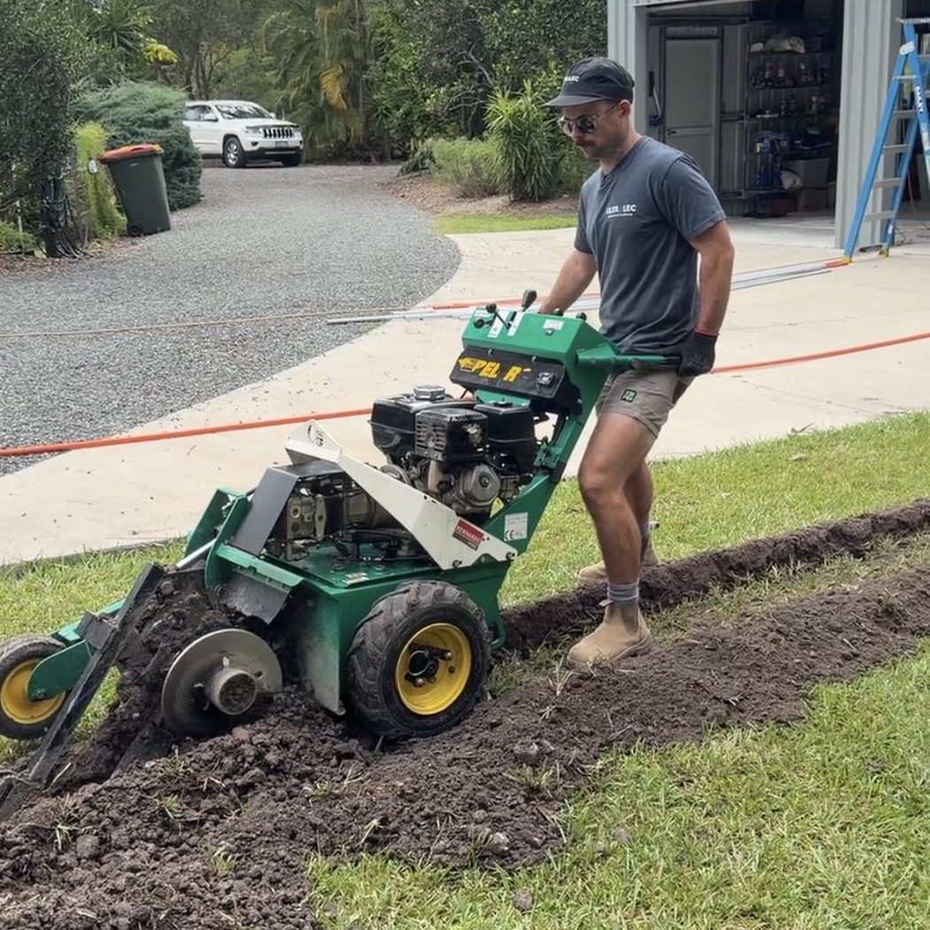 Alex from Ultralec operating a cable trenching machine to lay underground power — underground electrical installation Pomona Noosa Hinterland